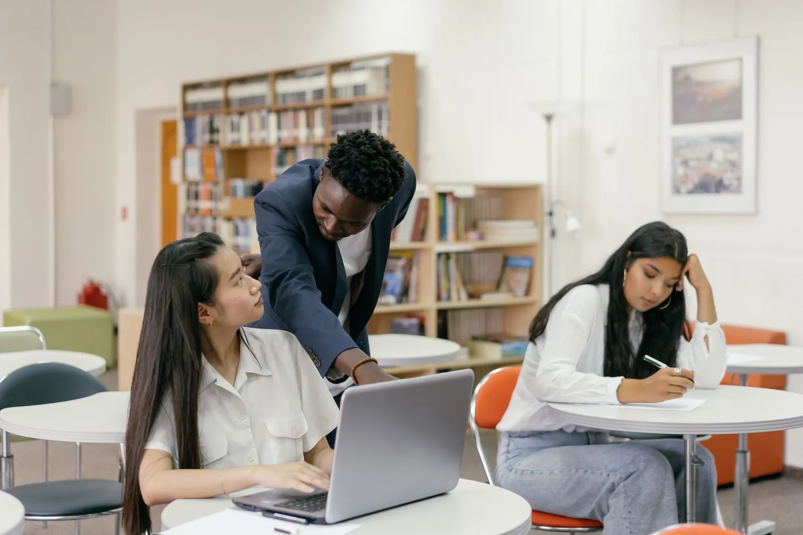Mentor guiding a student working on a laptop
