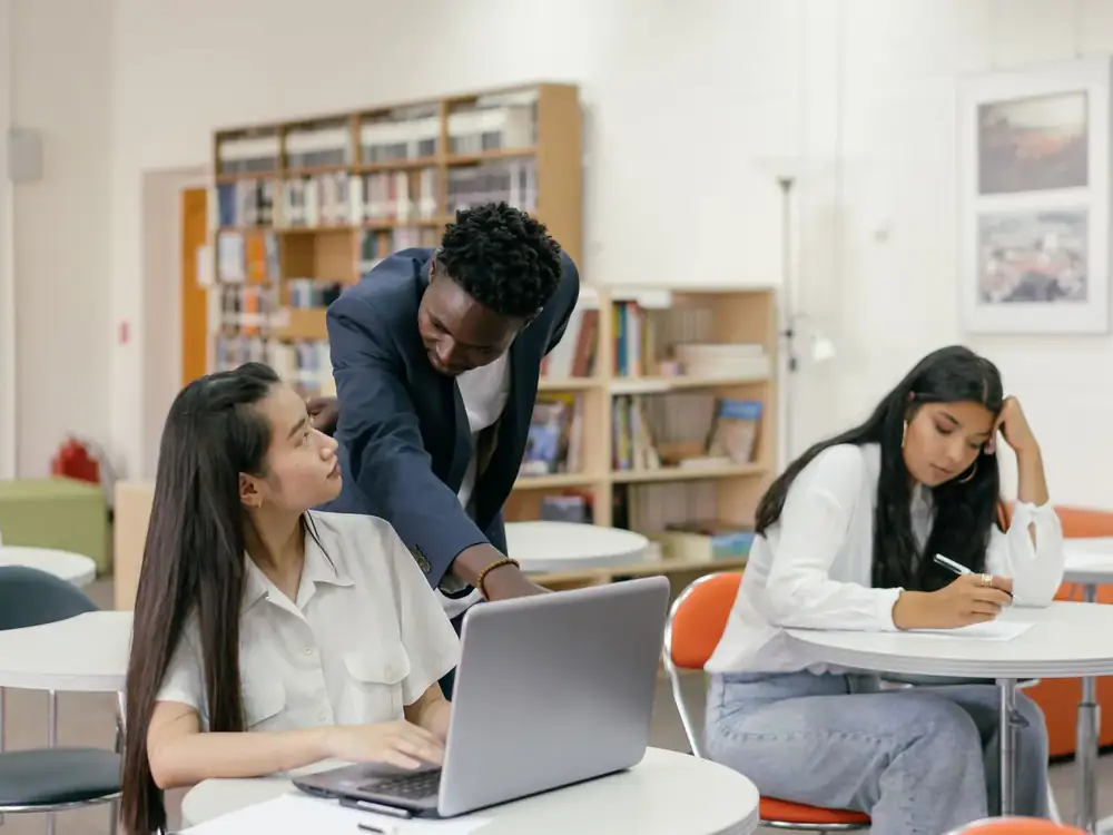 Mentor guiding a student working on a laptop