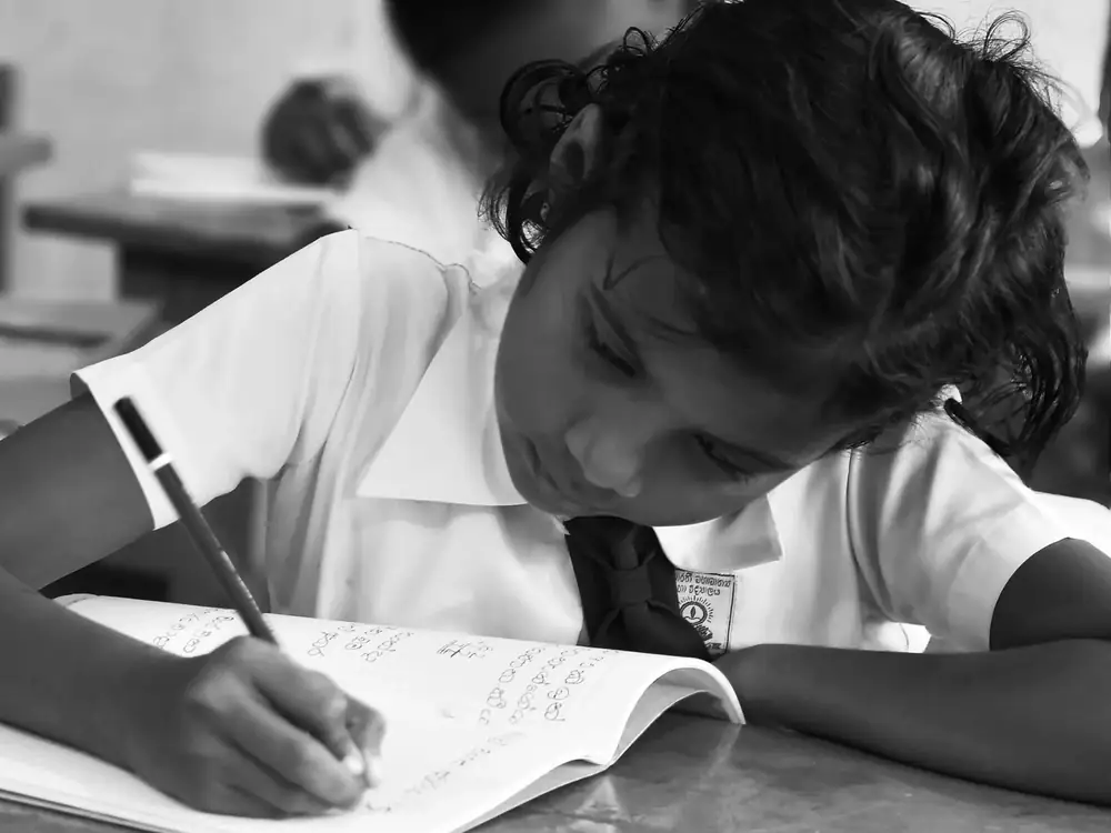 Student writing in a notebook in a classroom